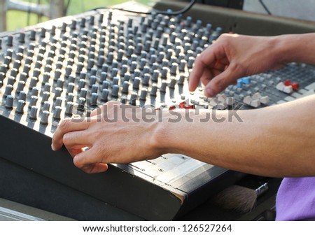 Image of hand of technician doing sound mixing console on sound board