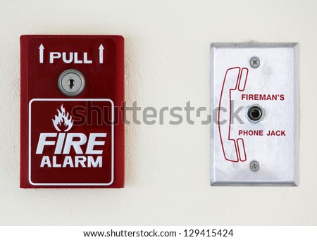 Fire alarm switch over a sign showing a fire and text fire alarm on a wall
