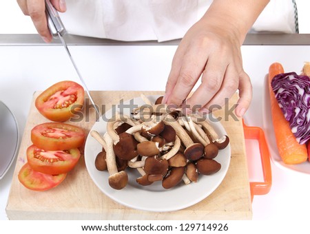 Image of woman holding knife and select mushrooms prepare for dinner