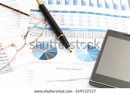 image of graphics and finance report for business with pen glasses and mobile phone
