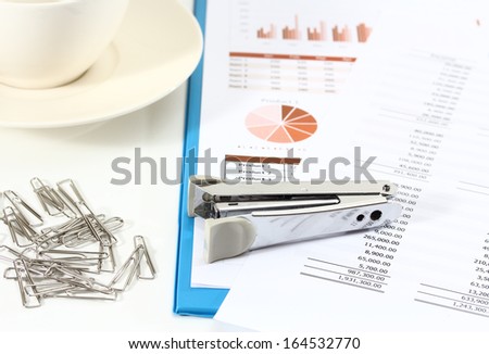 image of graphics and finance report for business with paper clips stapler and coffee