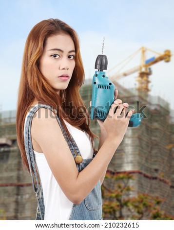 woman worker holding drill on hand for her job at workplace