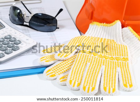 Image of calculator glasses helmet gloves and business report for construction on white desk