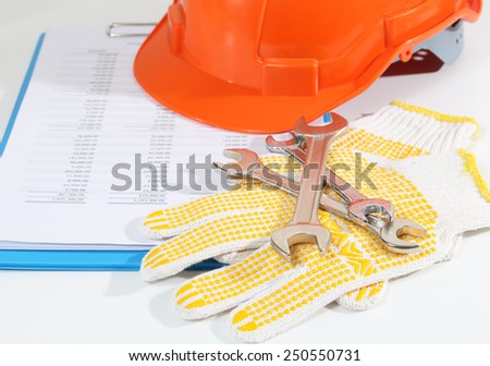 Image of gloves tools helmet and business report for construction on white desk