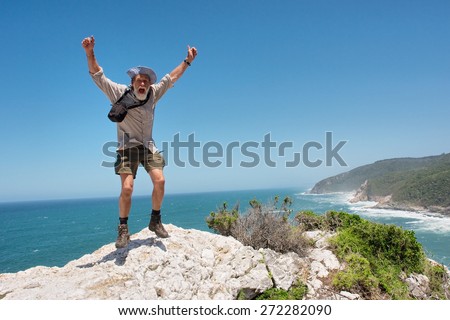 Happy jumping old man against beach background. Shot on the Otter trail in the Tsitsikamma National Park, Garden Route area, Western Cape, South Africa.
