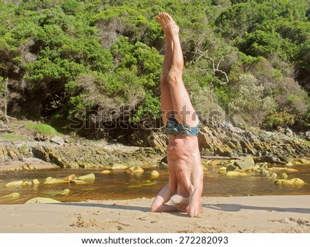 Old man doing yoga on beach. Shot on the Otter trail in the Tsitsikamma National Park, Garden Route area, Western Cape, South Africa.