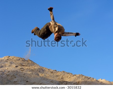 Teenager performs open-arms somersault on sand hill. Shot in the Dnieper sands, Ukraine.