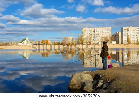 A fishing woman and a church. Shot on a stone embankment on the Dnieper river bay, in Poltavska region, Ukraine.