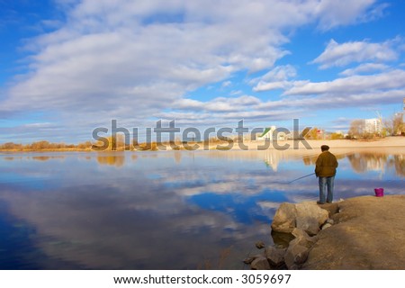 A fishing woman, church and skies. Shot on a stone embankment on the Dnieper river bay, in Poltavska region, Ukraine.
