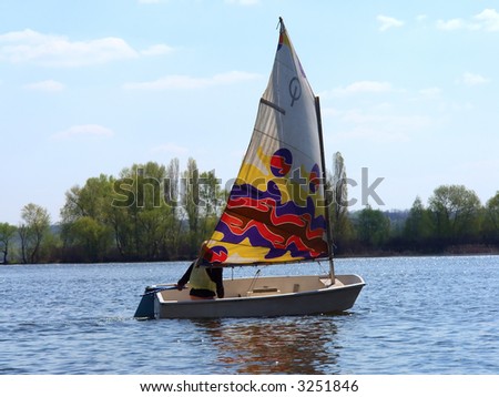 Blond girl drives a small yacht. Shot on the Dnieper river, Ukraine.