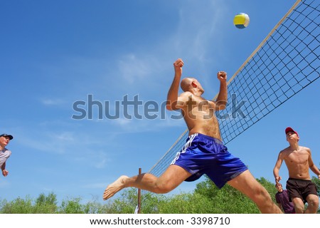 Four men playing beach volleyball - balding man runs after ball. Shot near Dnieper, Ukraine.