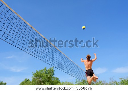Teenager plays beach volleyball - high jump with strike. Shot near Dnieper river, Ukraine.