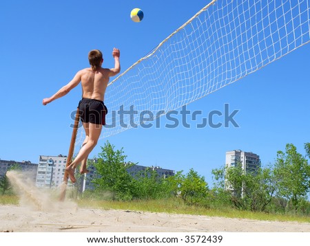Playing beach volleyball - teen jumps high after ball. Shot in Ukraine.