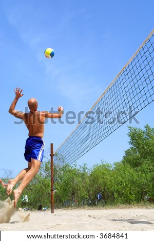 People playing beach volleyball - balding strong man spikes. Shot near Dnieper river, Ukraine.
