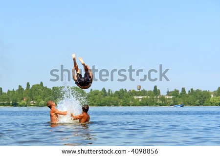 Teen jumps from hands into water in hot summer day. Shot in June, near Dnieper river (Dniepropetrovsk, Ukraine).