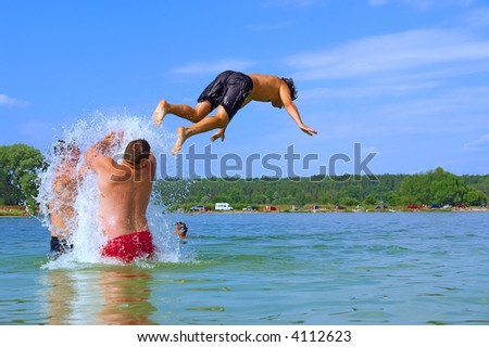 Two men push teenager high to jump in water. Shot in July near Kyiv, Ukraine.