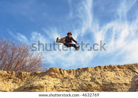 Teenager performs the open-leg jump from sand steep. Shot in the Dnieper sands, Ukraine.