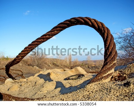 Thick rusty wire rope and ring in sand. Shot in an iron open-cast mine, Poltavska Region, Ukraine