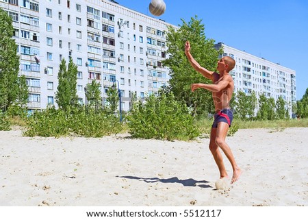 Young man plays beach volleyball - pushes ball. Shot in July, near Dnieper river, Ukraine.