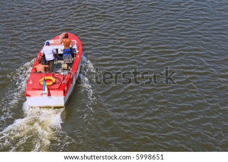 Red racing motor boat with three men on river. Shot on Dnieper river, Ukraine.