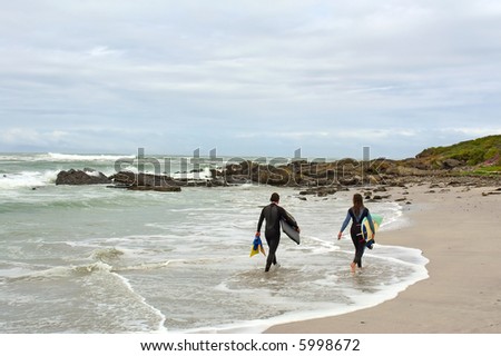 Two tired surfers walk on beach. Shot on West Coast, between Grotto Bay nature reserve and Silwerstroomstrand, Western Cape, South Africa.