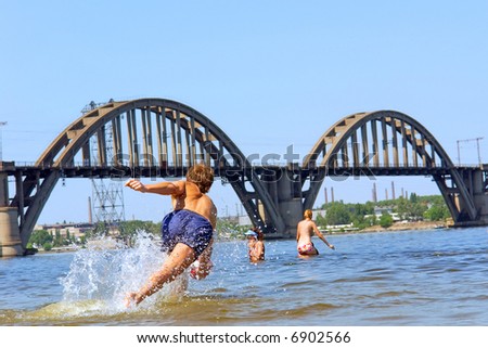 Boy jumps after ball in water in hot summer day. Shot in June, near Dnieper river (Dniepropetrovsk, Ukraine).
