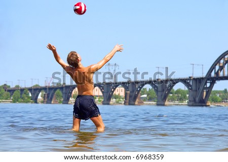 Boy hits the ball in water in hot summer day. Shot in June, near Dnieper river (Dniepropetrovsk, Ukraine).