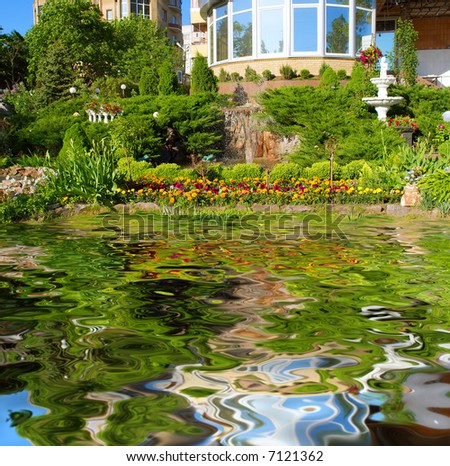 Beautiful pond in front of garden with sculptures, fountains and flowers - sunset light. Shot in Ukraine.
