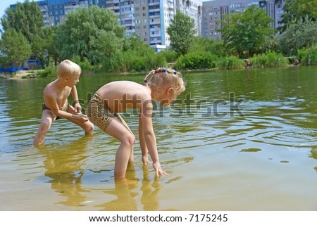 Kids throw stones into water in hot summer day. Shot in July, Dniepropetrovsk, Ukraine.