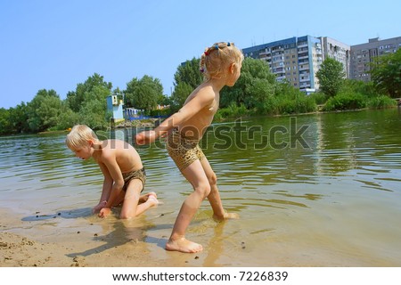 Throwing stones - two kids play on beach in hot summer day. Shot in Ukraine.
