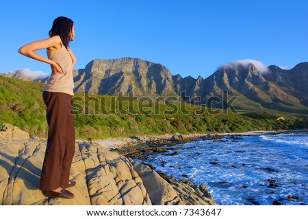 Girl looks at awesome sea and mountains - sunset light. Shot in Gordon/False Bay, Western Cape, South Africa.
