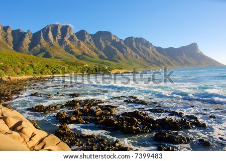 Beach with rocks and misty mountains in sunset light. Shot in Gordon/False Bay, Western Cape, South Africa.
