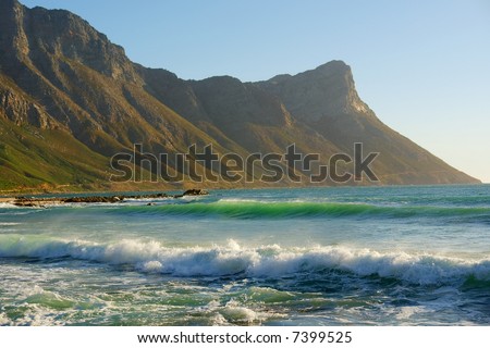 Green waves and mountain in mist - sunset light. Shot in Gordon/False Bay, Western Cape, South Africa.