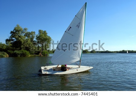 Small yacht gets out of river bay. Shot in July, Dnieper river, Ukraine.