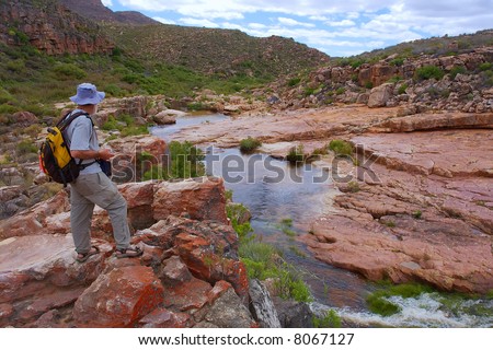 Old man looks from rock at small river. Shot in Cederberg Mountains, Western Cape, South Africa.