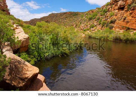Little river winds between red mountains. Shot in Sandrift (Dwarsrivier), Cederberg Mountains, Western Cape, South Africa.