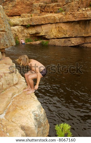 Young man is about to jump into water from rock. Shot in Sandrift, Cederberg Mountains, Western Cape, South Africa.