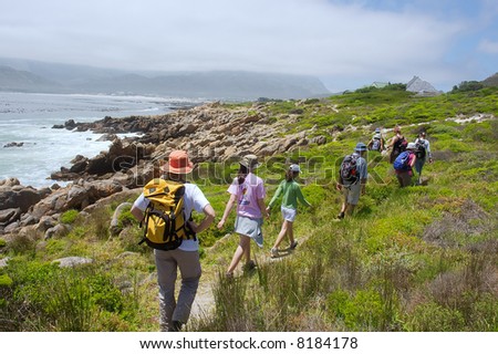 Group of hikers walks on sea beach to mountains. Shot near Strand, Pringle and Betties Bays, Western Cape, South Africa.