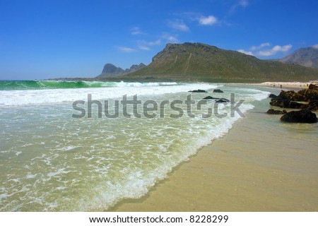 Three waves go on beach next to Hangklip mountain. Shot near Strand, Pringle and Betties Bays, Western Cape, South Africa.