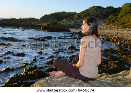 Meditating colored girl on sea shore - sunset light. Shot in Gordon/False Bay, Western Cape, South Africa.