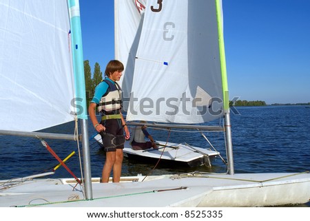 Teen boy stands on yacht deck. Shot in July, Dnieper river, Ukraine.