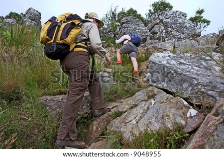 Two hikers climb on mountain. Shot in the Helderberg Mountains nature reserve, Western Cape, South Africa.