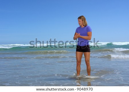 Young man stands in water on sea beach. Shot in Hermanus, Walker Bay, Western Cape, South Africa.