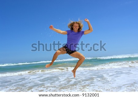 Happy man jumps high on sea beach with splashes. Shot in Hermanus, Walker Bay, Western Cape, South Africa.