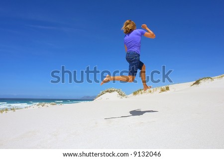 Young man runs uphill on sea beach under dramatic skies. Shot in Hermanus, Walker Bay, Western Cape, South Africa.