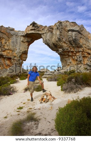 Young man poses in front of mountain arch. Shot in Wolfberg Mountains, Cederberg, Western Cape, South Africa.