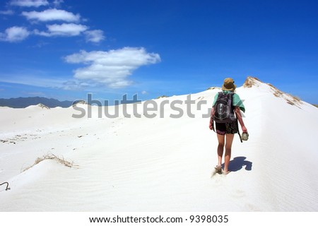 Woman walks uphill dune under dramatic skies. Shot in Hermanus, Walker Bay, Western Cape, South Africa.