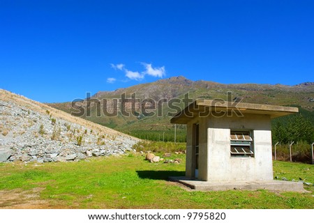 Small watch house in majestic mountains. Shot in Jonkershoek Nature Reserve dam, near Stellenbosch, Western Cape, South Africa.