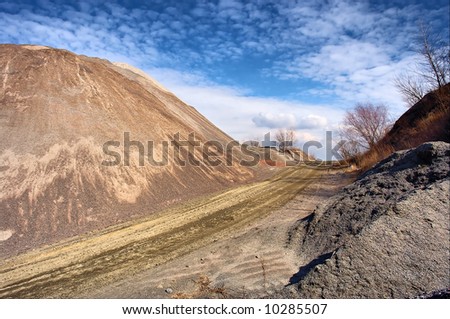 Artificial stone hill and road to clouds - dramatic light. Shot in March, in a stone open-cast mine, Poltavska Region, Ukraine