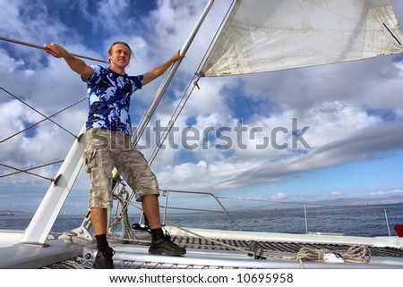 Happy man on sailboat desk against thunderstorm sky. Shot near Waterfront, Cape Town, Western Cape, South Africa.